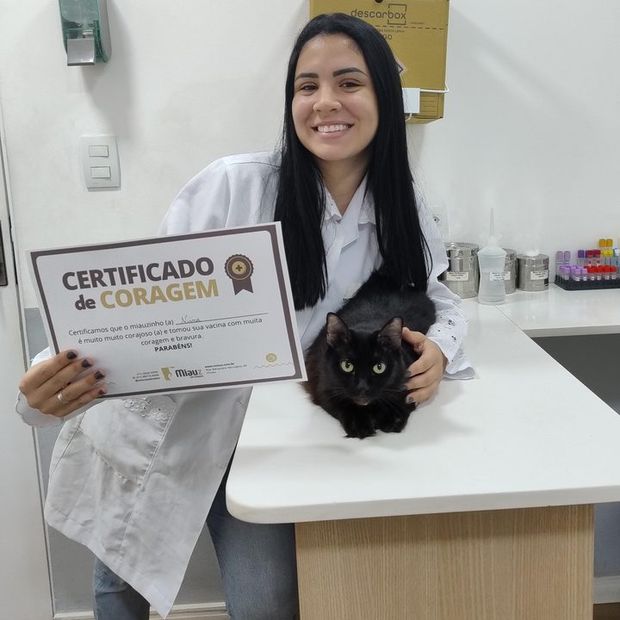 Veterinária da Miauz com o certificado de coragem entregue ao gato depois da vacina